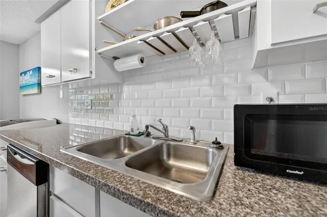 a kitchen with a sink a stove and a microwave with granite countertops