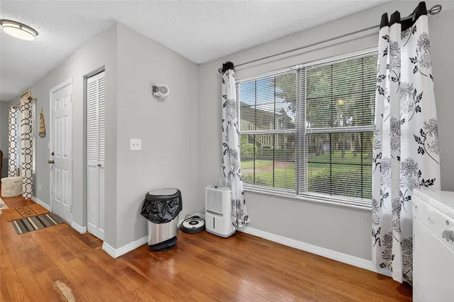 a view of an empty room with a window and wooden floor