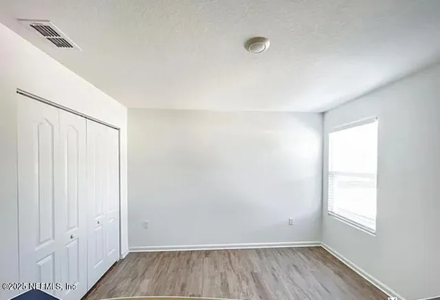 an empty room with wooden floor and windows