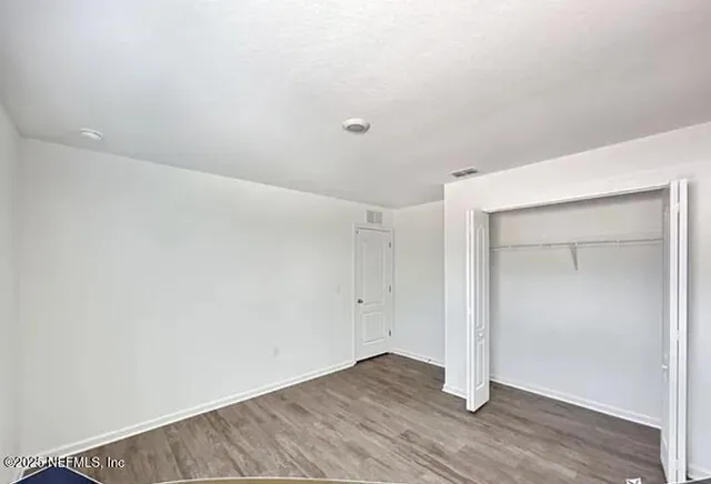 an empty room with wooden floor and closet