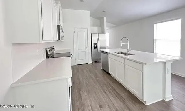 a kitchen with white cabinets appliances and sink