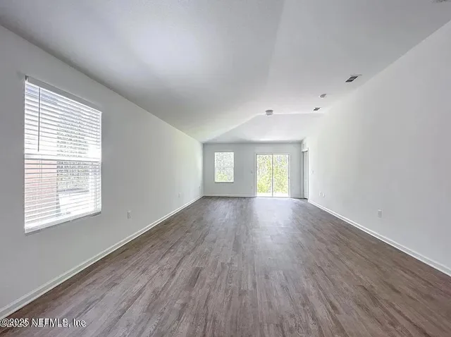 a view of empty room with window and wooden floor