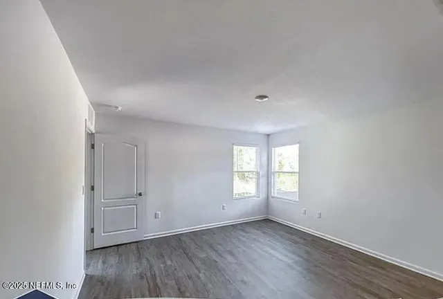 an empty room with wooden floor and window