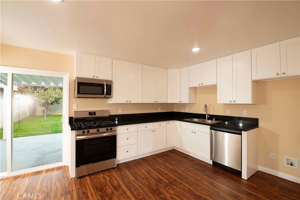 22729 Marbella Avenue Carson, CA 90745 - Photo 41 of 57 a kitchen with granite countertop a stove top oven a sink a counter space and wooden floor