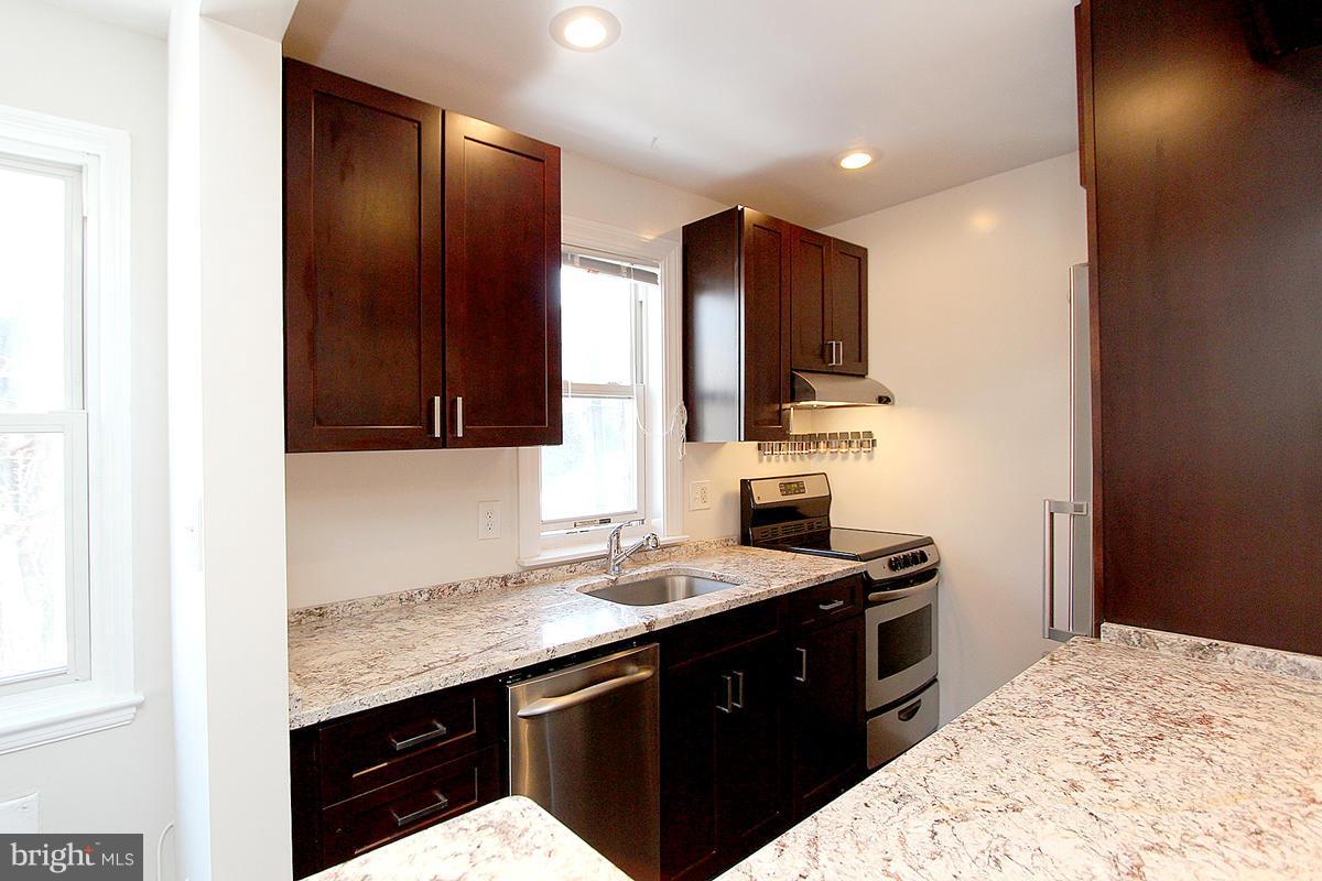 4000 Beecher Street Northwest, Unit 101 Washington, DC 20007 - Photo 24 of 26 a kitchen with stainless steel appliances granite countertop a sink stove and refrigerator