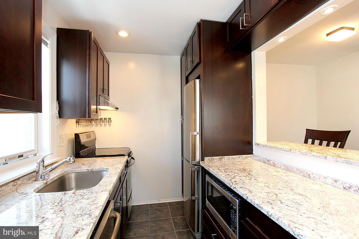 4000 Beecher Street Northwest, Unit 101 Washington, DC 20007 - Photo 25 of 26 a kitchen with a granite countertop sink and refrigerator