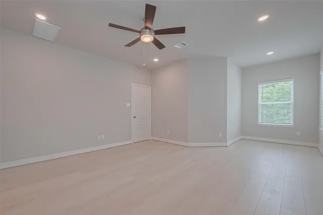 an empty room with a window and a fan