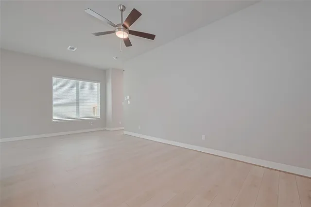 an empty room with a window and a ceiling fan