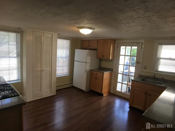 a kitchen with granite countertop a refrigerator a sink a stove and wooden floor