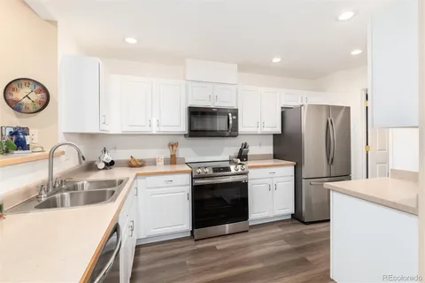 a kitchen with a sink a stove a refrigerator and a stove top oven with wooden floor