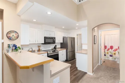 a kitchen with a refrigerator a stove top oven a sink a dining table and chairs with wooden floor