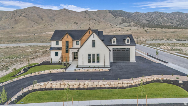 2828 Jojo Road Eagle Mountain, UT 84005 - Photo 57 of 63 Contemporary residence featuring white and wood-finish siding, a dark roof, and an attached two-car garage