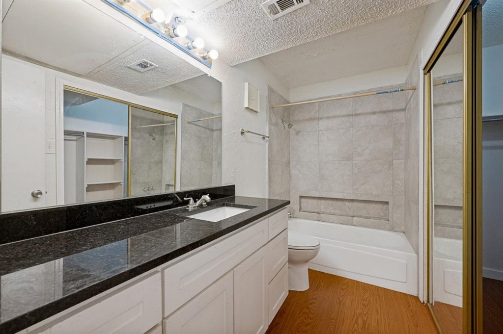 9206 Rodeo Drive Irving, TX 75063 - Photo 19 of 25 a bathroom with a granite countertop sink a toilet a mirror and shower