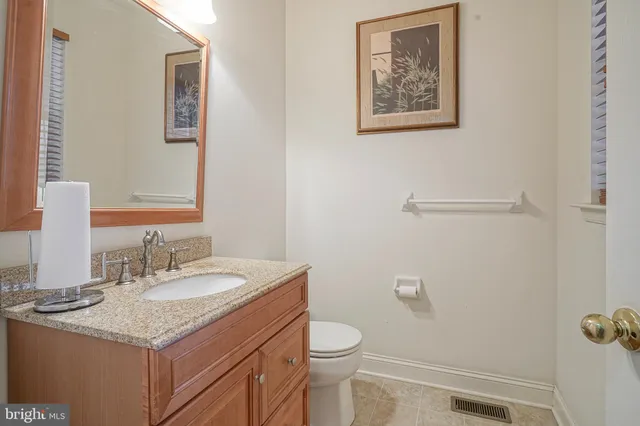 a bathroom with a granite countertop sink mirror vanity and toilet