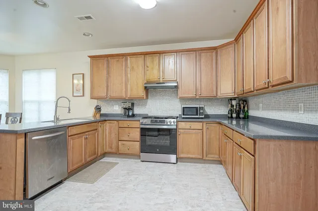 a kitchen with granite countertop a sink stove and cabinets