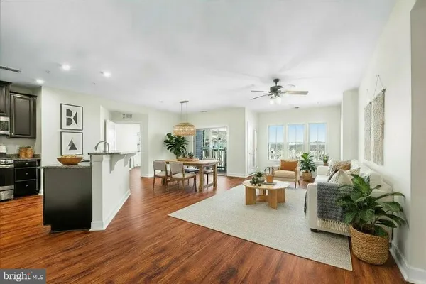 a living room with furniture kitchen view and a wooden floor