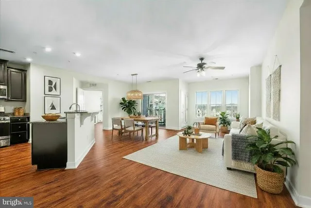 a living room with furniture kitchen view and a wooden floor