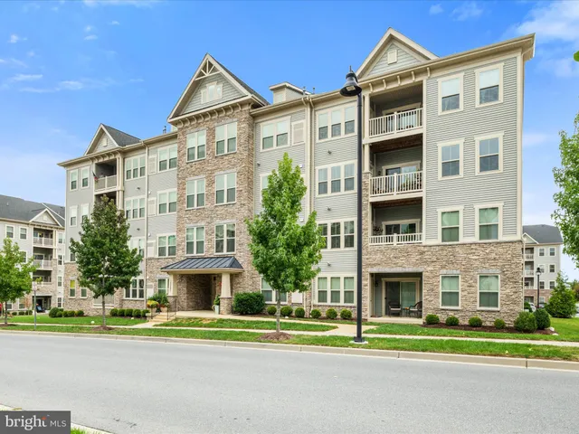 a front view of a residential apartment building with a yard and plants