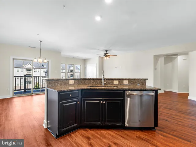 a kitchen with stainless steel appliances granite countertop a sink and a wooden floor