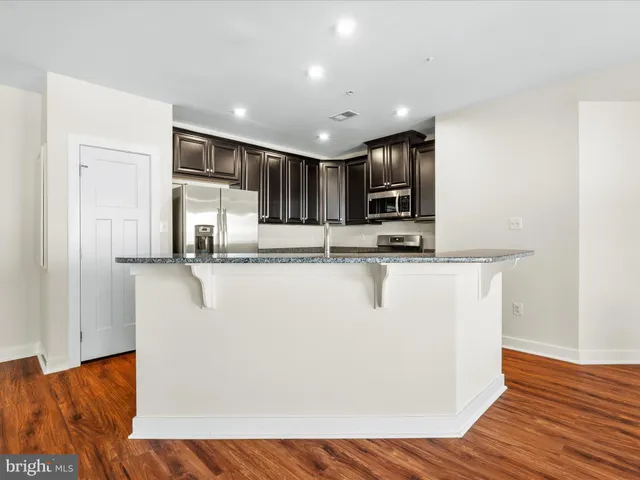 a view of kitchen with stainless steel appliances granite countertop a refrigerator a stove a sink and a microwave