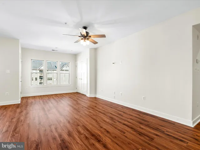 a view of room with hardwood floor and a ceiling fan