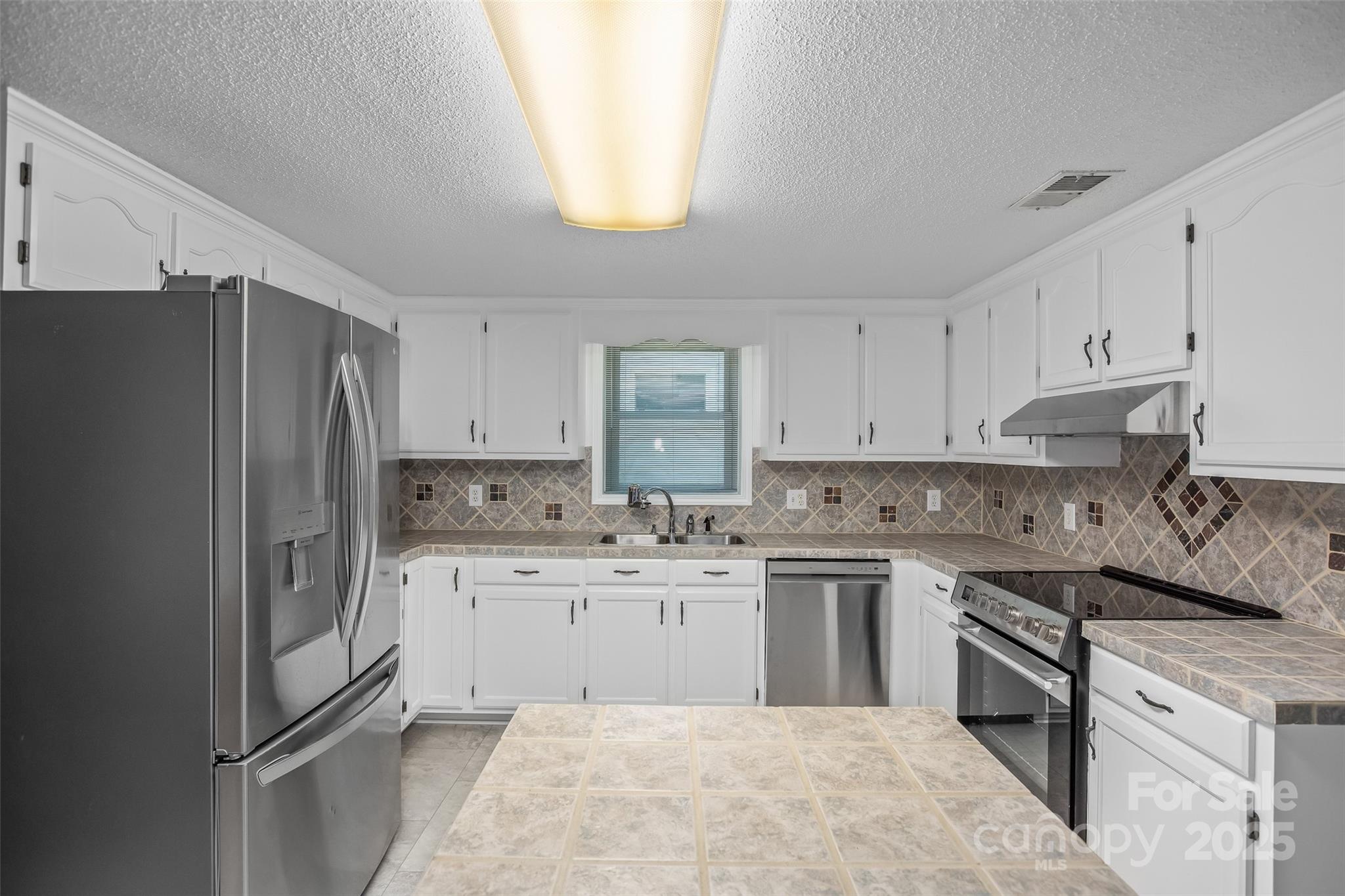 188 Nicks Road, Unit 20/21 Norwood, NC 28128 - Photo 7 of 20 a kitchen with a sink a refrigerator a stove and white cabinets