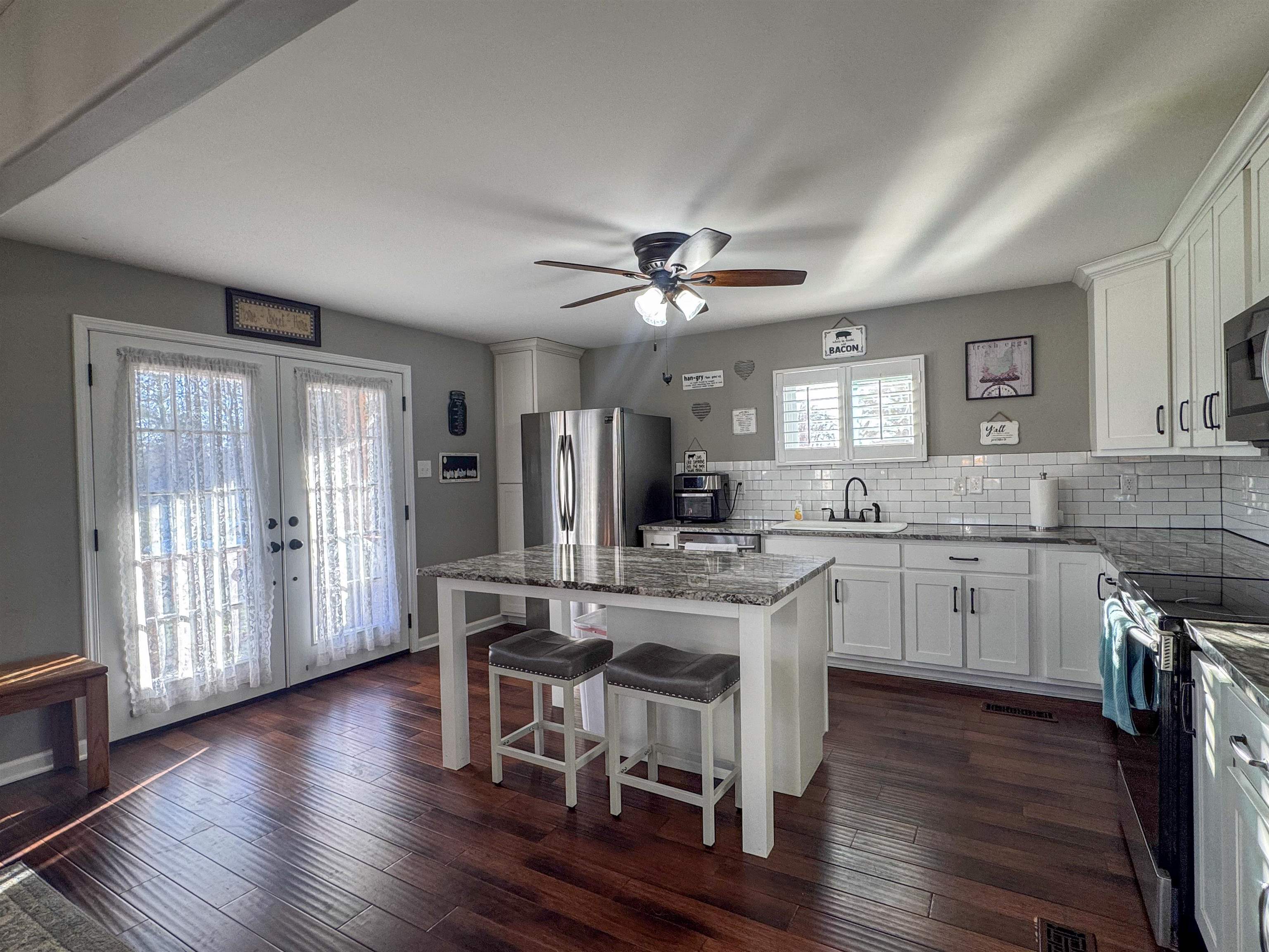 792 Smith Drive Covington, TN 38019 - Photo 15 of 34 Kitchen with dark stone countertops, french doors, a kitchen island, and white cabinets