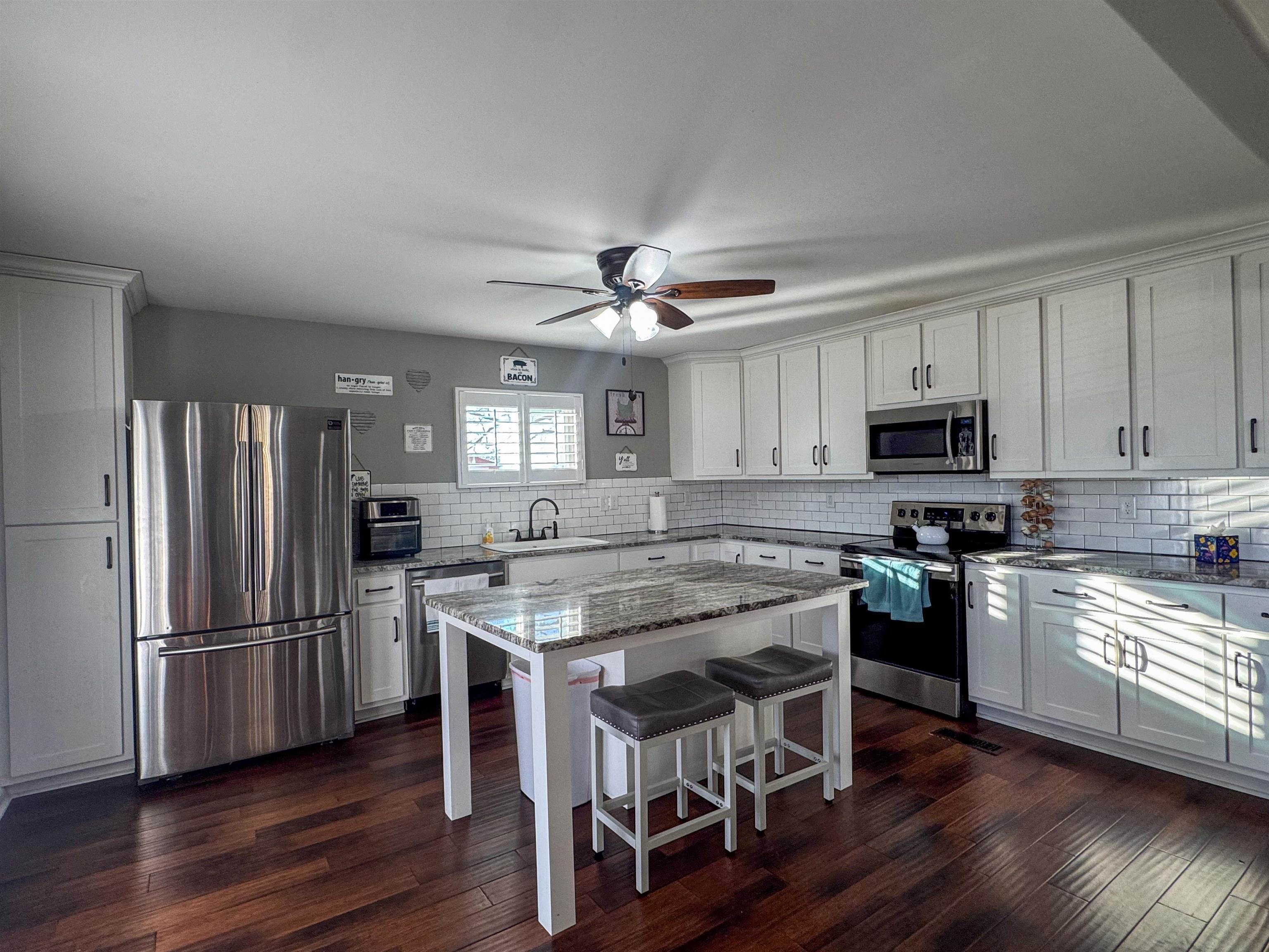 792 Smith Drive Covington, TN 38019 - Photo 16 of 34 Kitchen featuring stainless steel appliances, light stone counters, white cabinets, and a kitchen bar