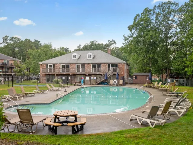 a view of a swimming pool with lawn chairs and a yard