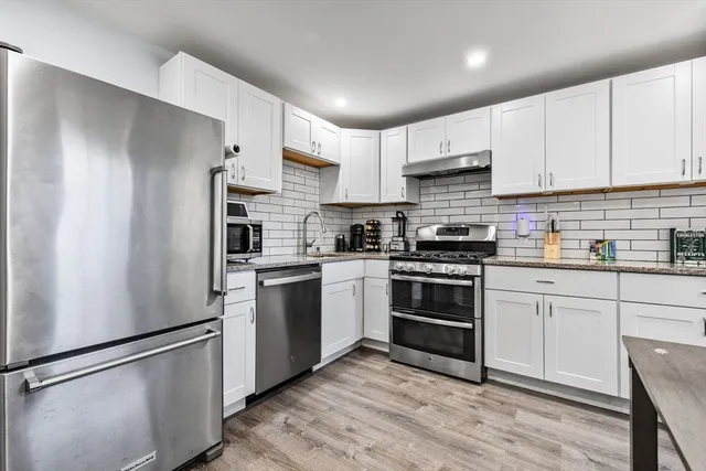 a kitchen with stainless steel appliances white cabinets and a refrigerator