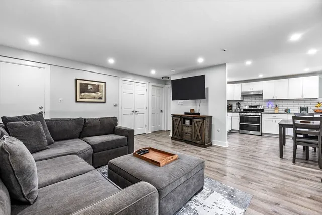 a living room with furniture kitchen view and a wooden floor