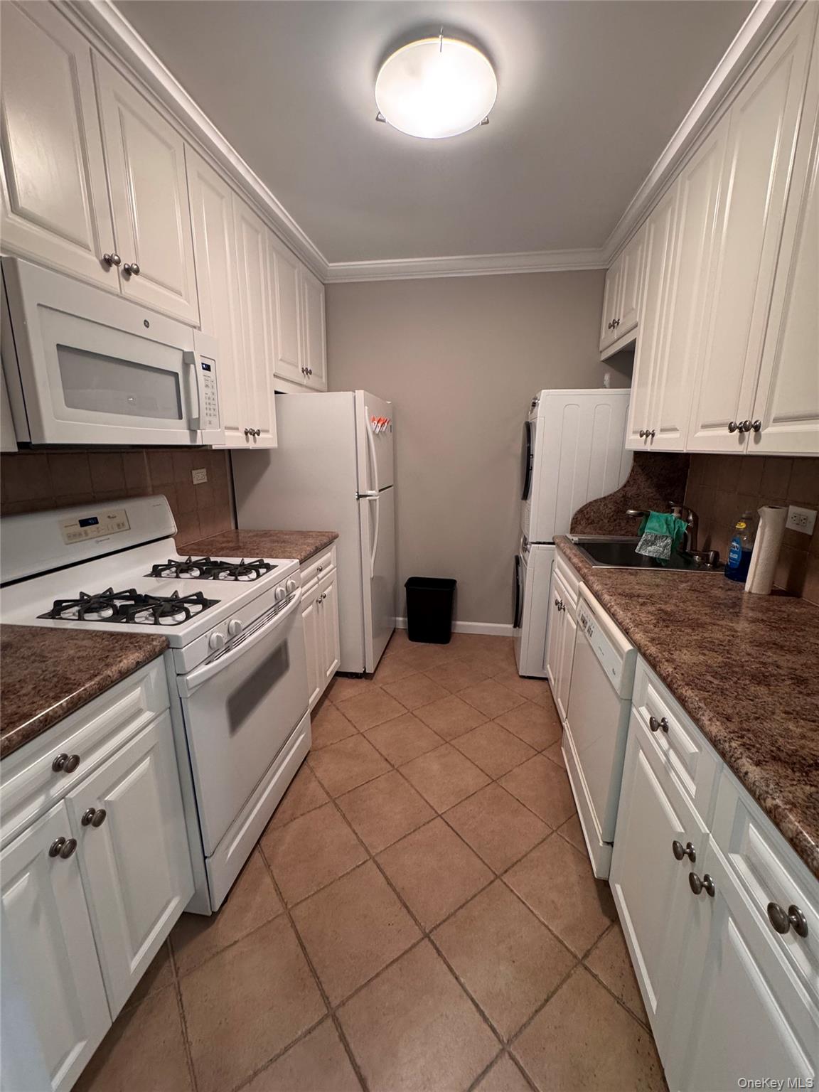 269 Grand Central Parkway, Unit 2C Queens, NY 11005 - Photo 14 of 18 Kitchen featuring tasteful backsplash, white appliances, white cabinets, and crown molding