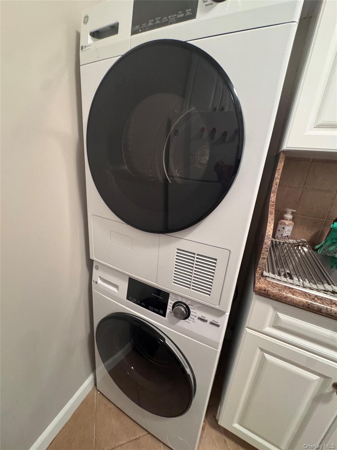 269 Grand Central Parkway, Unit 2C Queens, NY 11005 - Photo 15 of 18 Laundry room with light tile patterned floors and stacked washing machine and dryer