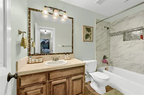 a bathroom with a sink a toilet a mirror a vanity and shower