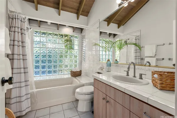 a bathroom with a granite countertop sink toilet a large mirror a bathtub and next to a window
