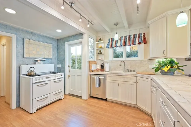 a kitchen with cabinets stainless steel appliances and wooden floor