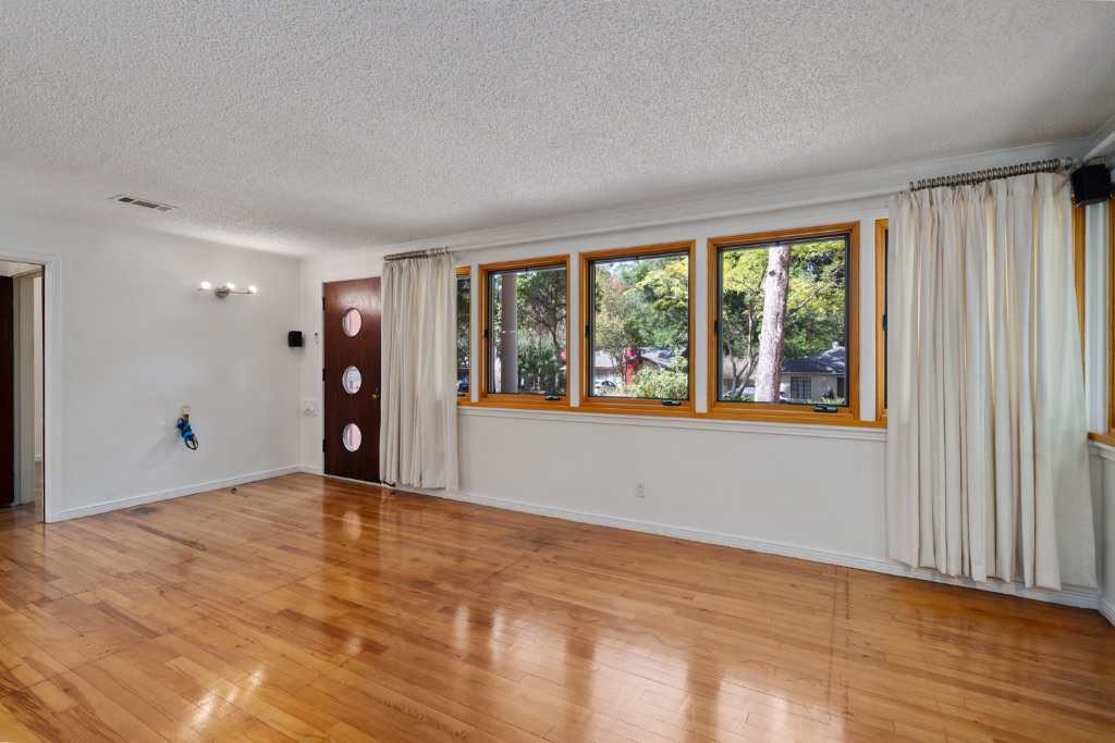 1212 Bentwood Road Austin, TX 78722 - Photo 7 of 32 a view of an empty room with a window and wooden floor