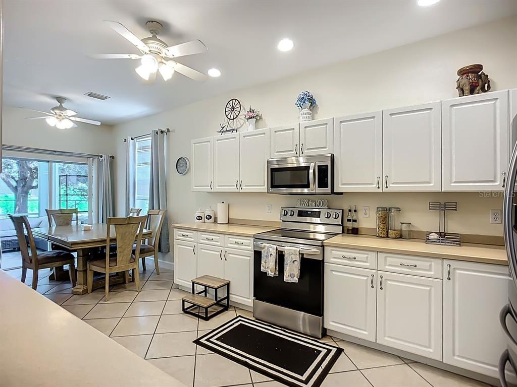 394 Sunset Road Rotonda West, FL 33947 - Photo 13 of 41 a kitchen with stainless steel appliances a white stove top oven cabinets a dining table and chairs