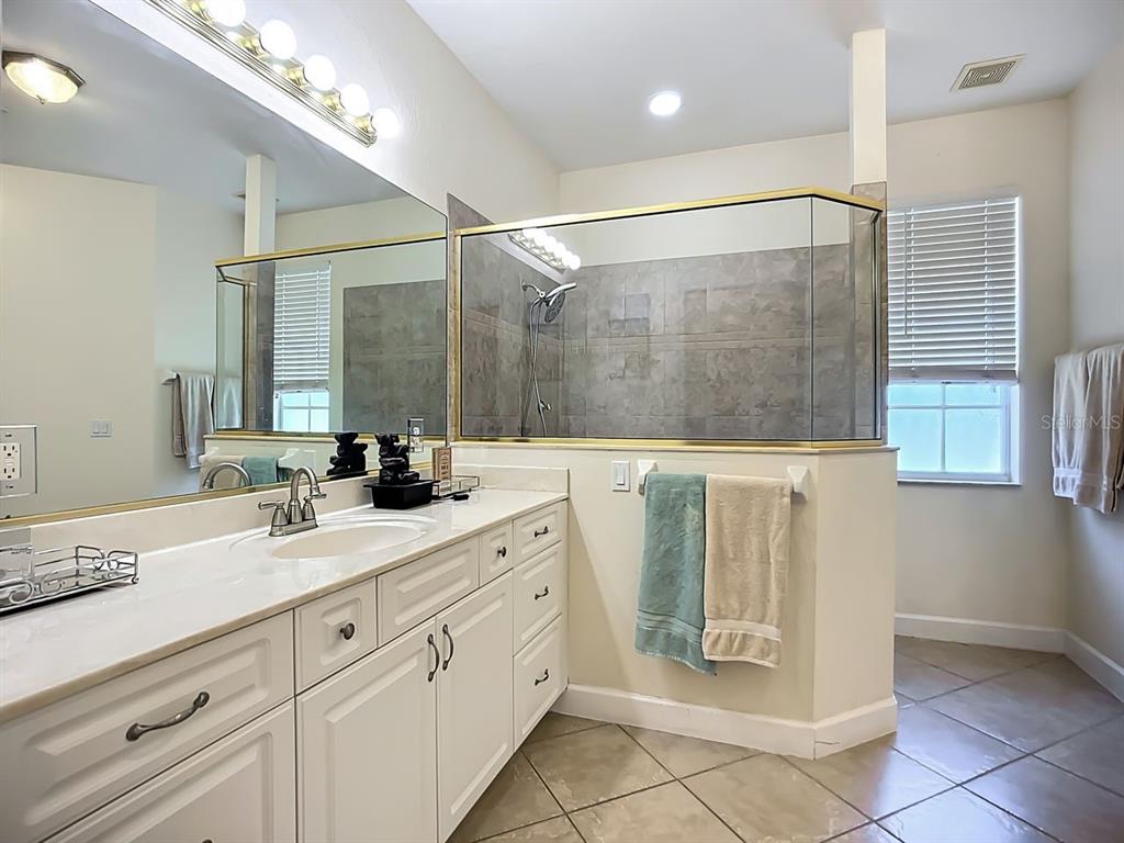 394 Sunset Road Rotonda West, FL 33947 - Photo 21 of 41 a spacious bathroom with a granite countertop sink a mirror and a shower