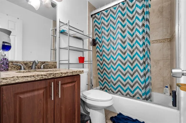 a bathroom with a granite countertop toilet sink and mirror