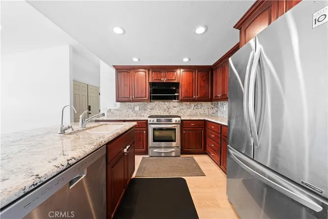 a kitchen with stainless steel appliances granite countertop a stove a sink and a refrigerator