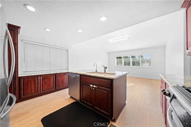 a kitchen with stainless steel appliances granite countertop a refrigerator a sink dishwasher a stove and white countertops with wooden floor