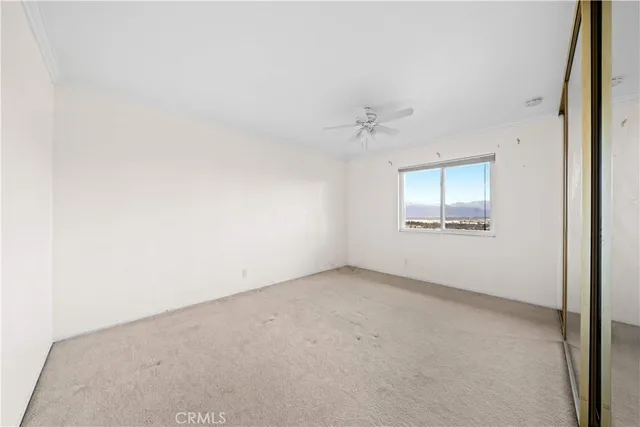 an empty room with a chandelier fan and windows