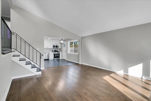 a view of staircase and kitchen with wooden floor and pendant lights