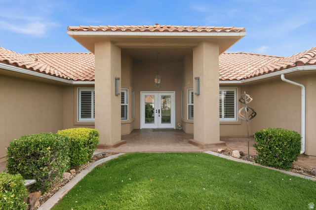 1985 West Rivers Edge Lane St. George, UT 84770 - Photo 11 of 42 Property entrance with french doors, a patio area, stucco siding, and a lawn