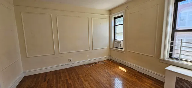 a view of an empty room with wooden floor and a window