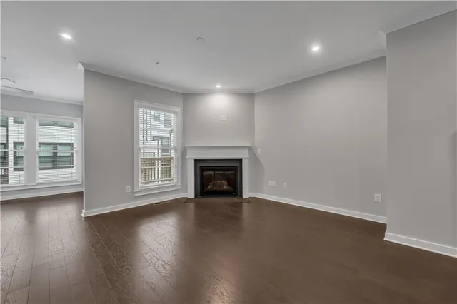 an empty room with wooden floor fireplace and windows