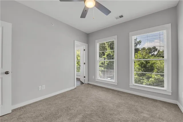 an empty room with ceiling fan and window