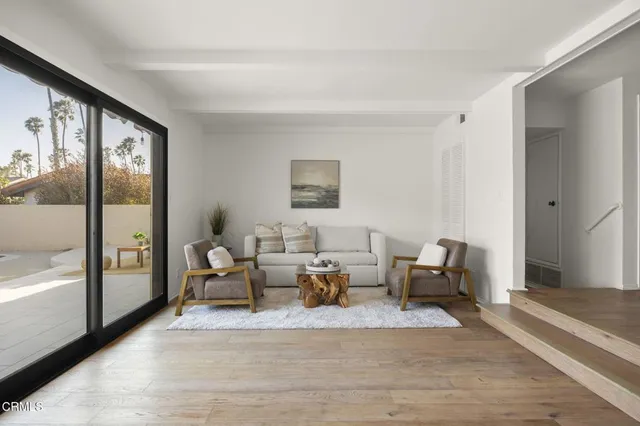 a living room with furniture large window and a wooden floor