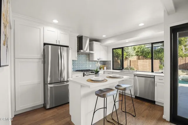 a kitchen with refrigerator a sink and chairs